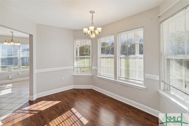 unfurnished dining area featuring a notable chandelier and dark wood-type flooring