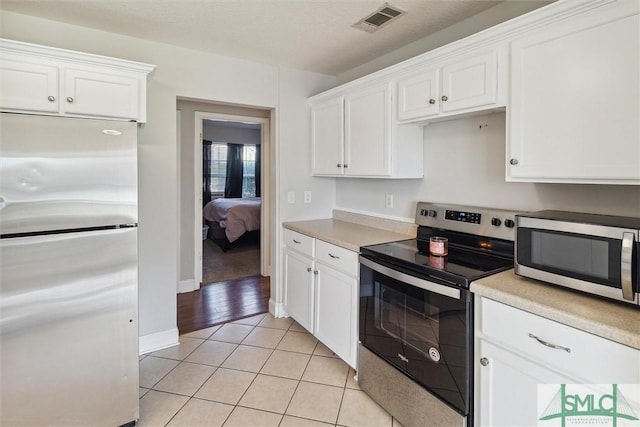 kitchen featuring white cabinets, light tile patterned flooring, and appliances with stainless steel finishes