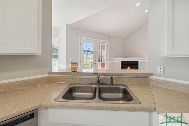 kitchen with white cabinetry, french doors, sink, stainless steel dishwasher, and vaulted ceiling