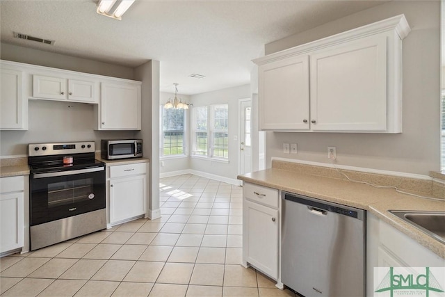 kitchen with a chandelier, appliances with stainless steel finishes, white cabinets, and light tile patterned floors