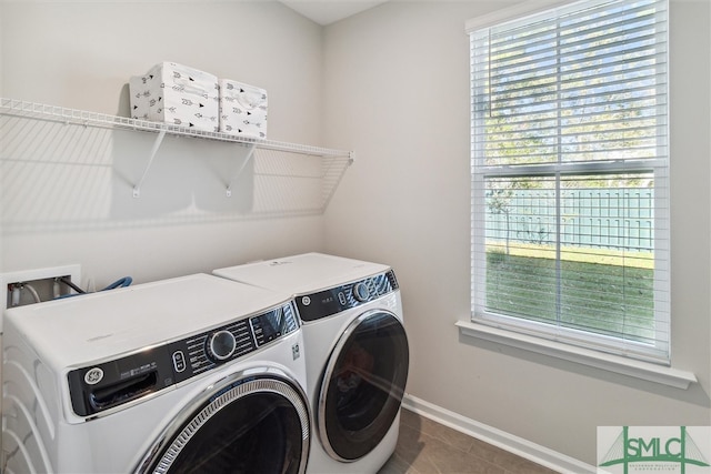 laundry room featuring washer and clothes dryer, dark tile patterned flooring, and plenty of natural light