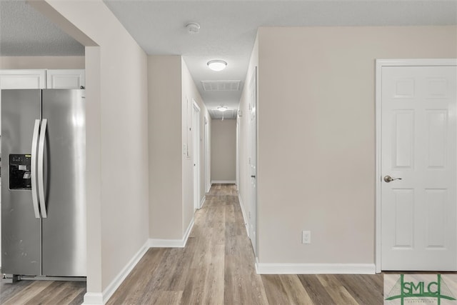 corridor featuring light hardwood / wood-style floors and a textured ceiling