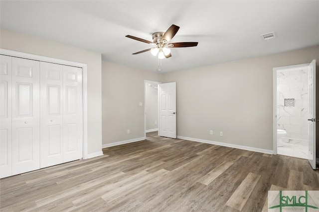 unfurnished bedroom featuring a closet, light hardwood / wood-style floors, ceiling fan, and ensuite bathroom