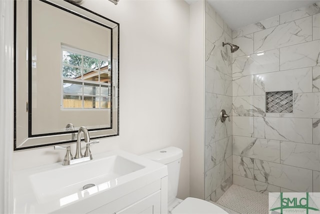 bathroom featuring a tile shower, vanity, and toilet