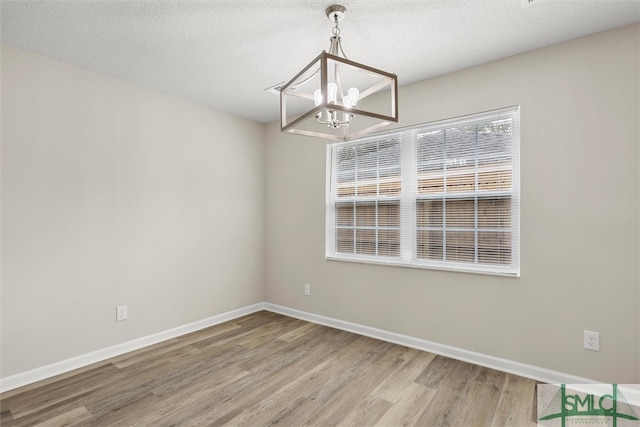 interior space featuring wood-type flooring, a textured ceiling, and a notable chandelier