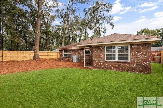 rear view of property with central air condition unit and a yard