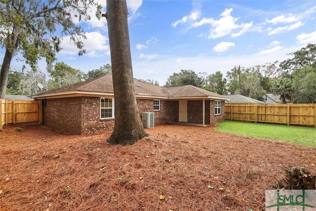 rear view of house featuring central AC unit and a lawn