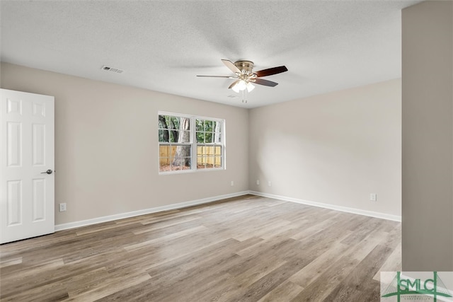 empty room with ceiling fan, light hardwood / wood-style flooring, and a textured ceiling