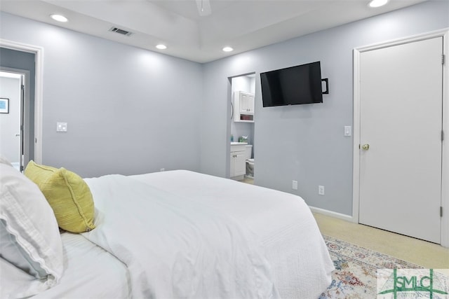 bedroom with light colored carpet, ceiling fan, and ensuite bathroom