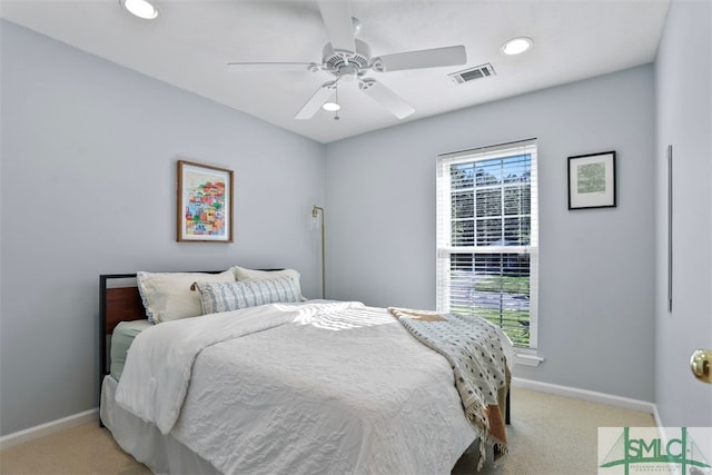 bedroom with multiple windows, ceiling fan, and light carpet