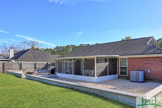 back of house with central air condition unit, a sunroom, and a lawn