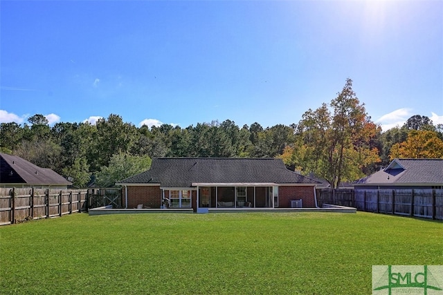 back of house with a sunroom and a lawn