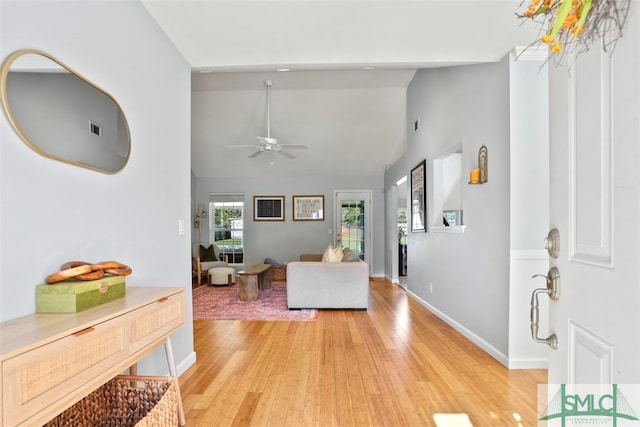 living room with ceiling fan, high vaulted ceiling, and light wood-type flooring