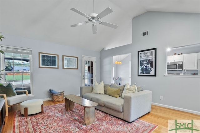 living room featuring light wood-type flooring, vaulted ceiling, and ceiling fan