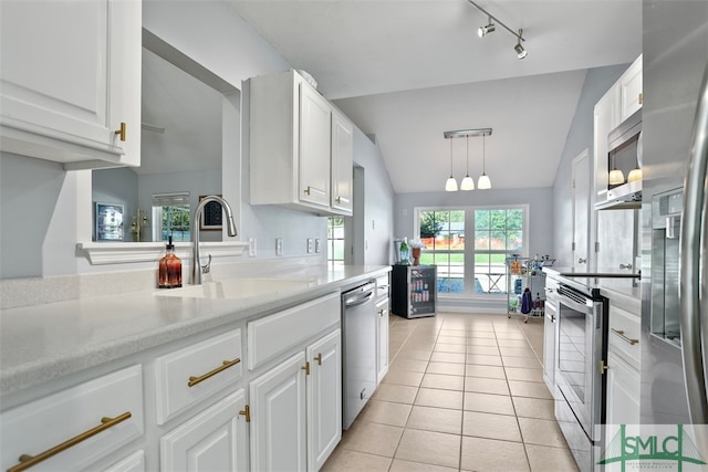 kitchen featuring white cabinetry, hanging light fixtures, vaulted ceiling, light tile patterned floors, and appliances with stainless steel finishes