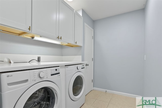 clothes washing area featuring cabinets, light tile patterned floors, and washing machine and clothes dryer