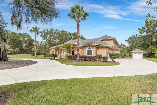 view of front of house featuring a garage, a front lawn, and an outdoor structure