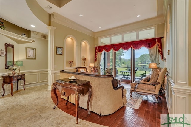 living room featuring ornate columns, wood-type flooring, and ornamental molding