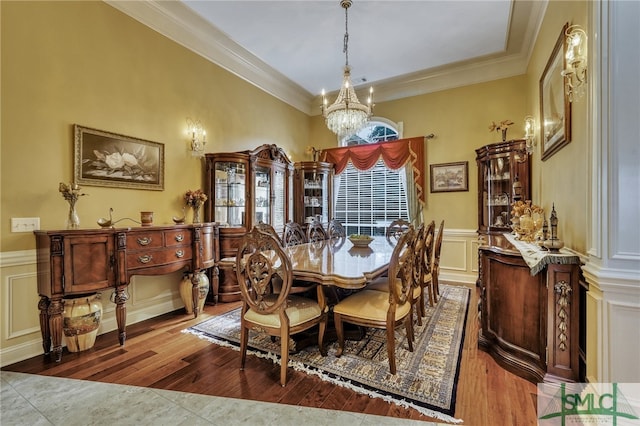 dining area with a chandelier, wood-type flooring, and crown molding