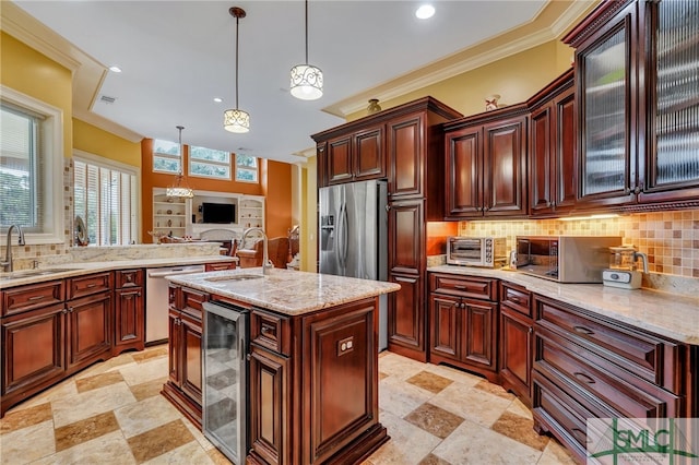 kitchen with appliances with stainless steel finishes, a kitchen island with sink, sink, wine cooler, and hanging light fixtures