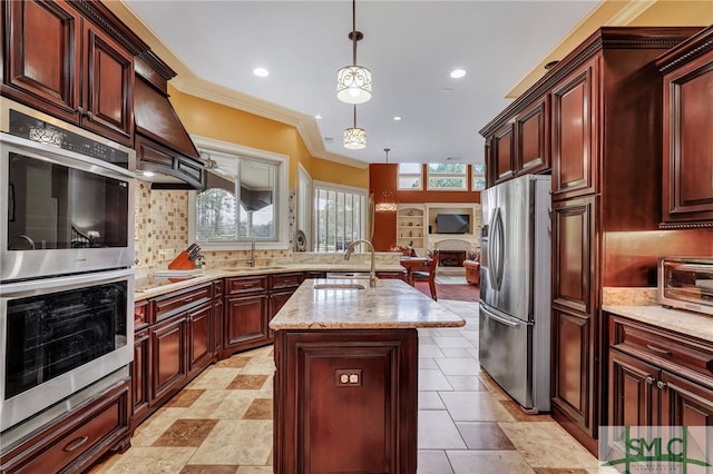 kitchen with pendant lighting, an island with sink, a healthy amount of sunlight, and appliances with stainless steel finishes