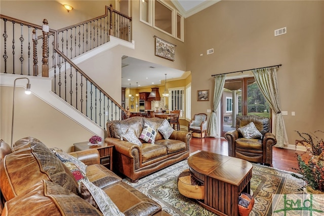 living room with ornamental molding, hardwood / wood-style floors, and a towering ceiling