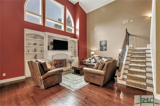 living room with ornamental molding, a towering ceiling, and hardwood / wood-style flooring