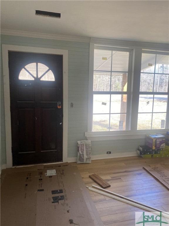 entrance foyer with wood-type flooring, plenty of natural light, and ornamental molding