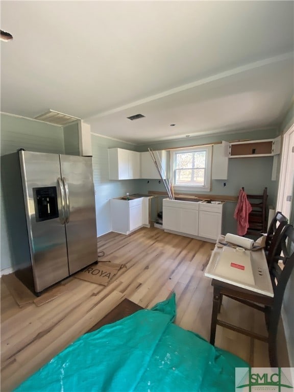 kitchen with stainless steel fridge with ice dispenser, white cabinets, and light wood-type flooring