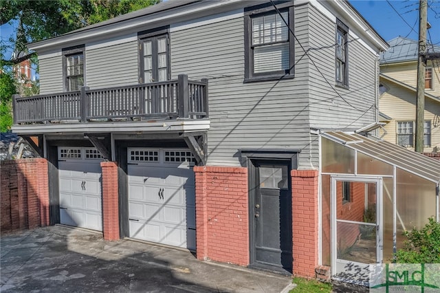 18 E 34th St, Savannah, GA 31401 - view of front of house featuring brick siding, a balcony, a garage, and asphalt driveway