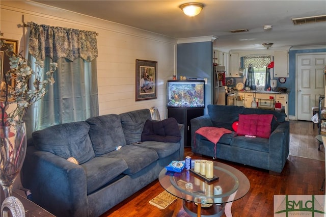 living room with wooden walls, ornamental molding, and dark hardwood / wood-style floors