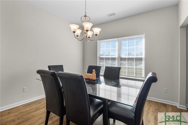 dining room with hardwood / wood-style floors and a chandelier