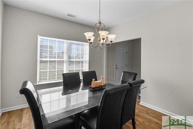 dining space with an inviting chandelier, a textured ceiling, and hardwood / wood-style flooring