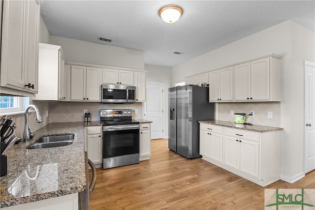 kitchen featuring appliances with stainless steel finishes, white cabinetry, and sink