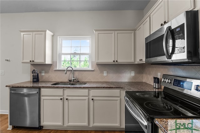 kitchen with white cabinets, sink, decorative backsplash, light wood-type flooring, and appliances with stainless steel finishes