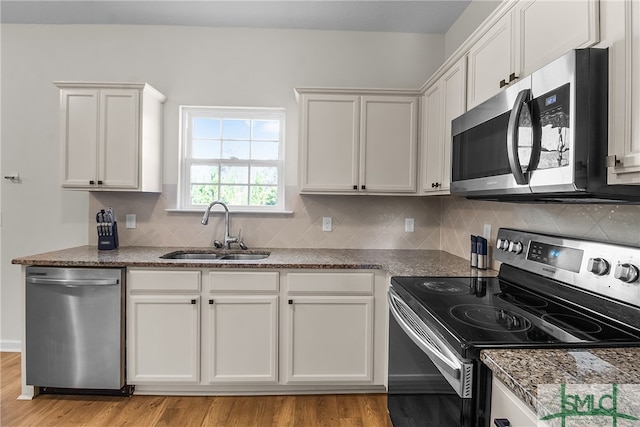 kitchen featuring backsplash, stainless steel appliances, sink, light hardwood / wood-style floors, and white cabinetry