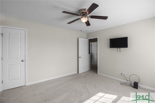 unfurnished bedroom with ceiling fan, light colored carpet, and a textured ceiling