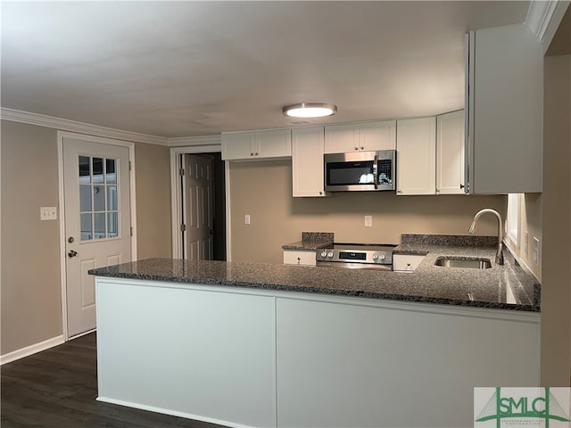 kitchen with kitchen peninsula, appliances with stainless steel finishes, sink, dark stone countertops, and white cabinets