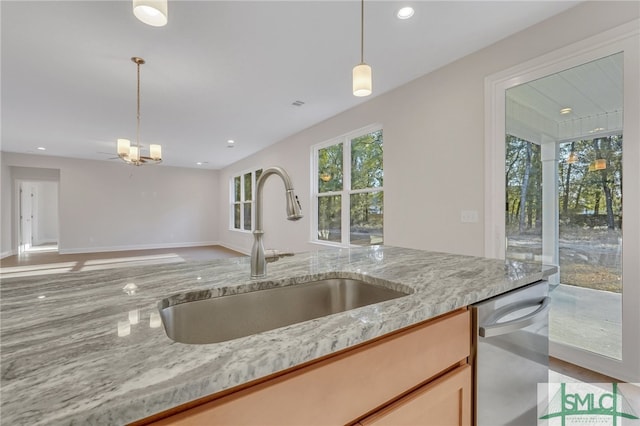 kitchen with dishwasher, decorative light fixtures, light stone countertops, and sink