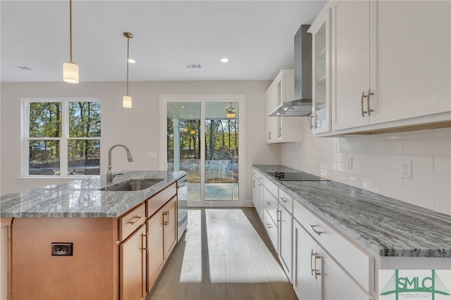 kitchen with white cabinetry, sink, and wall chimney range hood