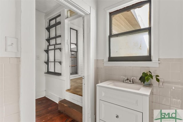 bathroom with hardwood / wood-style floors, plenty of natural light, tile walls, and vanity