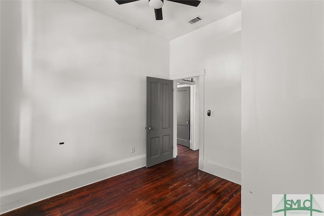 empty room with a towering ceiling, ceiling fan, and dark wood-type flooring