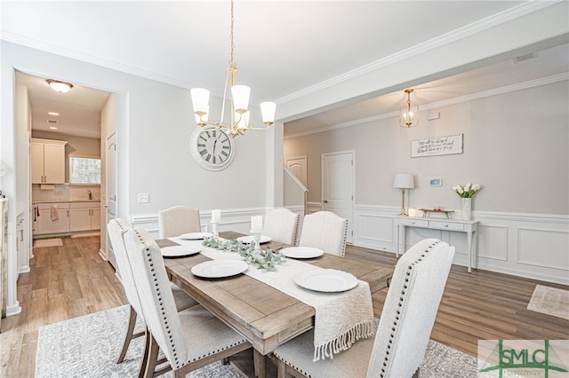 dining room featuring light hardwood / wood-style flooring, a chandelier, and ornamental molding