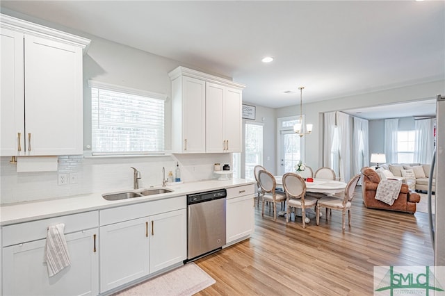 kitchen featuring sink, stainless steel dishwasher, decorative backsplash, light wood-type flooring, and white cabinetry