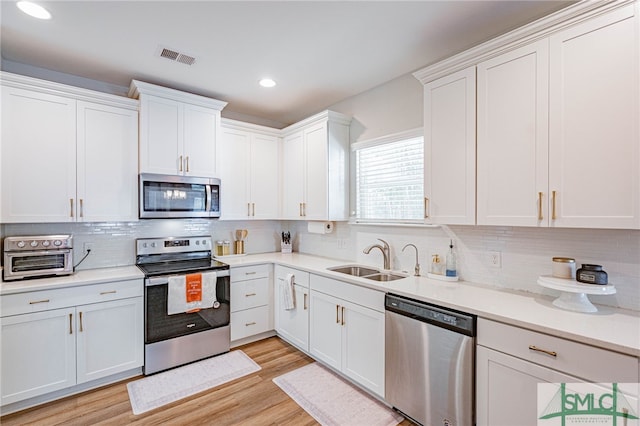 kitchen featuring appliances with stainless steel finishes, light hardwood / wood-style flooring, white cabinetry, and sink