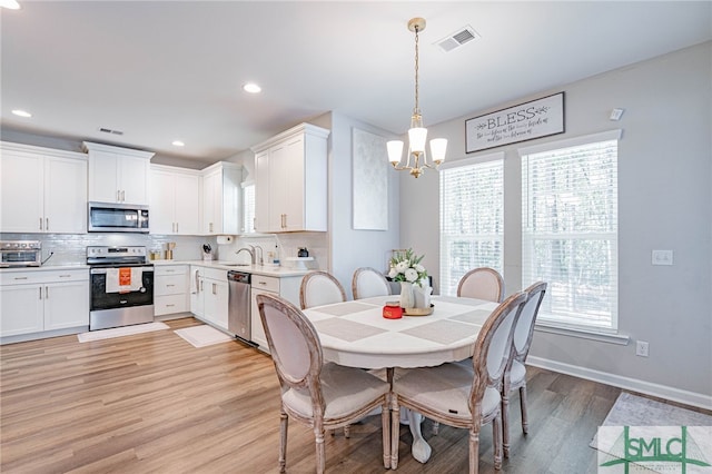 dining room with a chandelier, light wood-type flooring, and sink