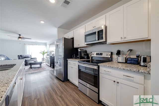 kitchen featuring light stone countertops, dark hardwood / wood-style flooring, white cabinets, and stainless steel appliances