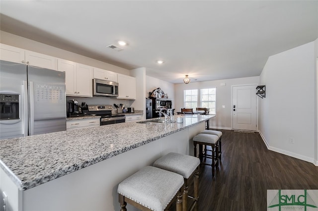 kitchen featuring light stone countertops, sink, dark hardwood / wood-style floors, a breakfast bar, and appliances with stainless steel finishes