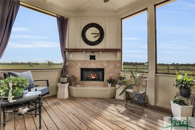 sunroom / solarium with a tile fireplace, a healthy amount of sunlight, and a rural view