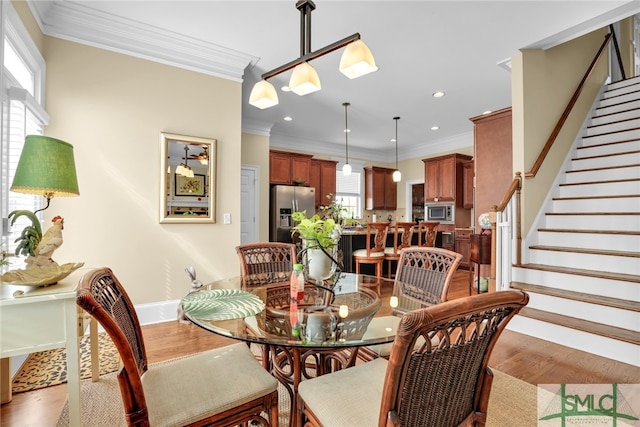 dining room featuring light hardwood / wood-style floors, ornamental molding, and a wealth of natural light